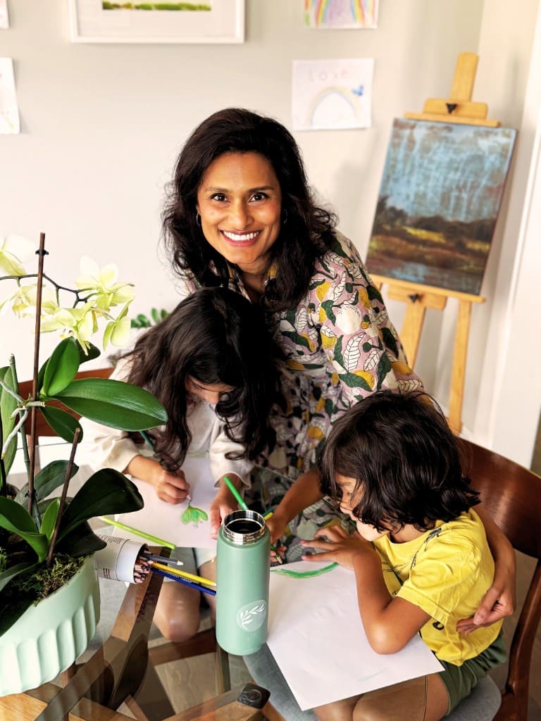 A mom and her kids drawing together at home, with a Signal for Peace sticker on a water bottle